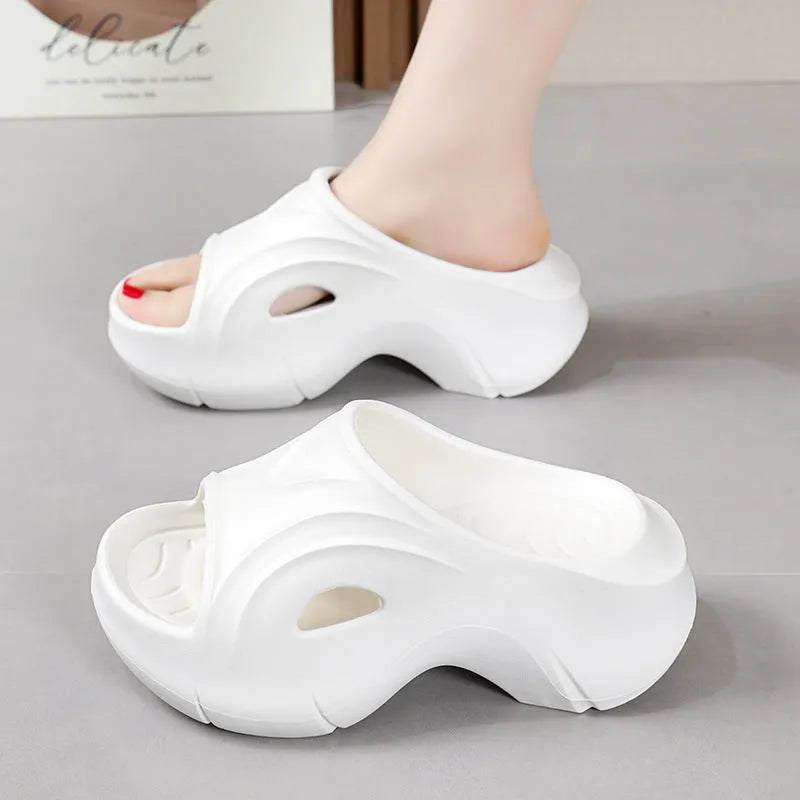 Women's white EVA slippers with a thick sole on a sandy beach background