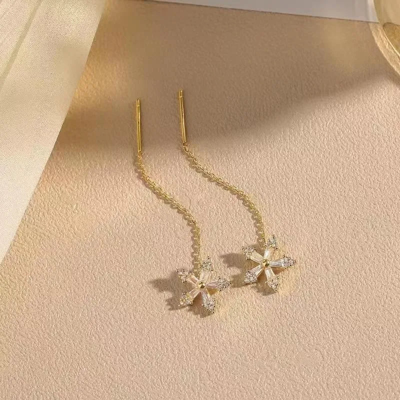 Long gold drop earrings for women with metal construction and secure fastening on white background