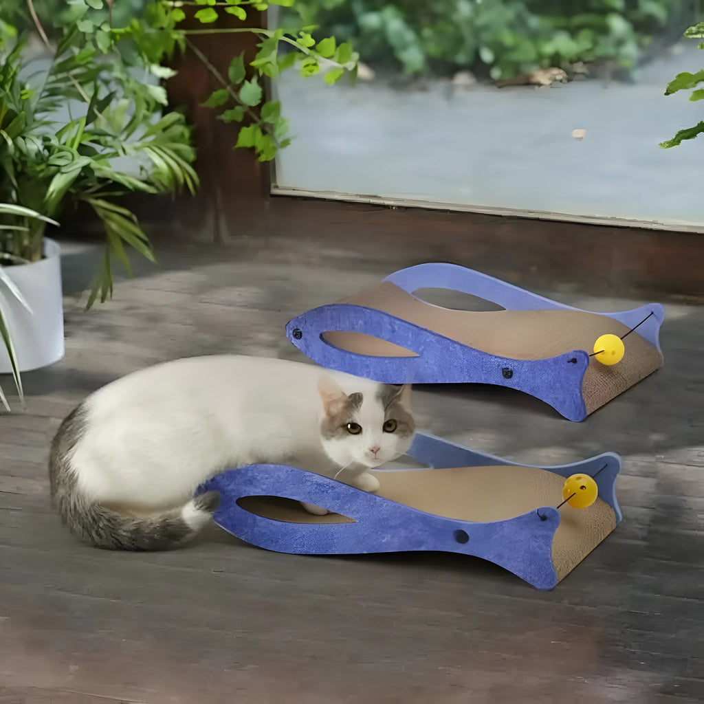 Blue fish-shaped cat scratcher pad with ball toy on elastic cord, cardboard construction with wavy lounge surface