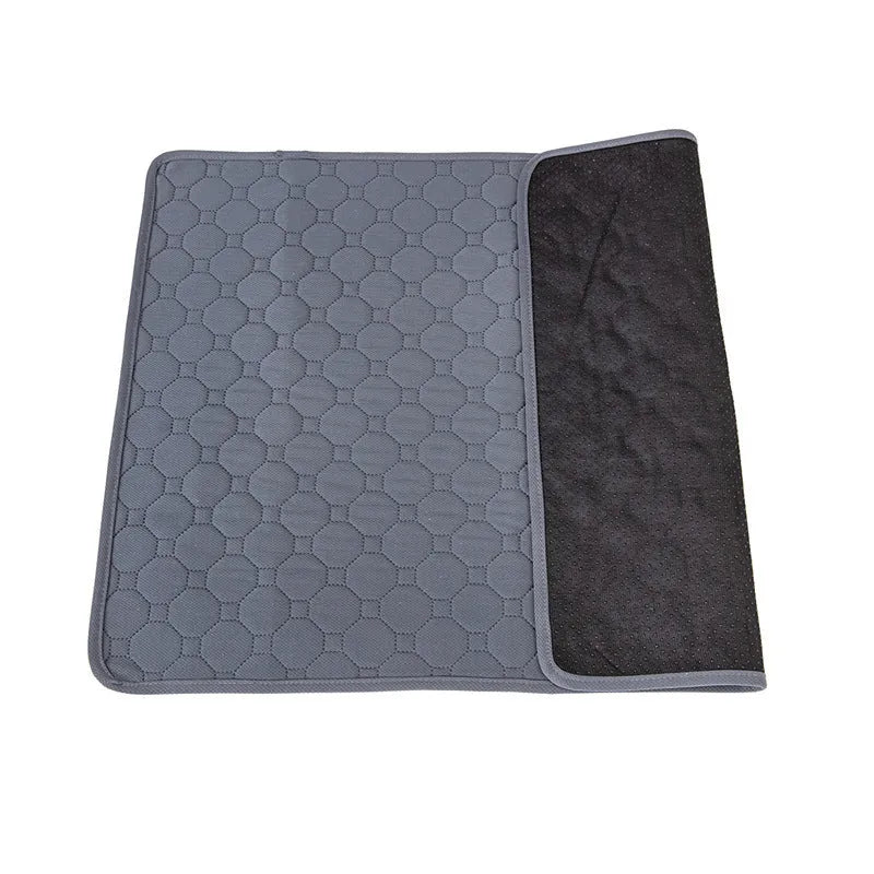 Grey and khaki washable waterproof dog pee pad on a wooden floor next to a pet crate.