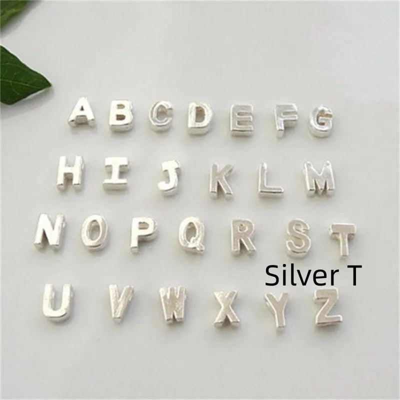 Golden peach heart shaped alloy necklace pendant with a letter design on a white background.