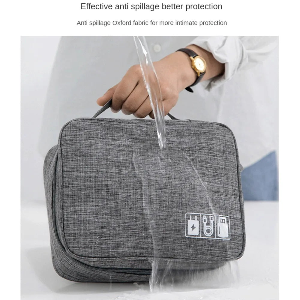 Black waterproof travel cable organiser bag open, showing mesh pockets, elastic loops, and removable padded dividers.