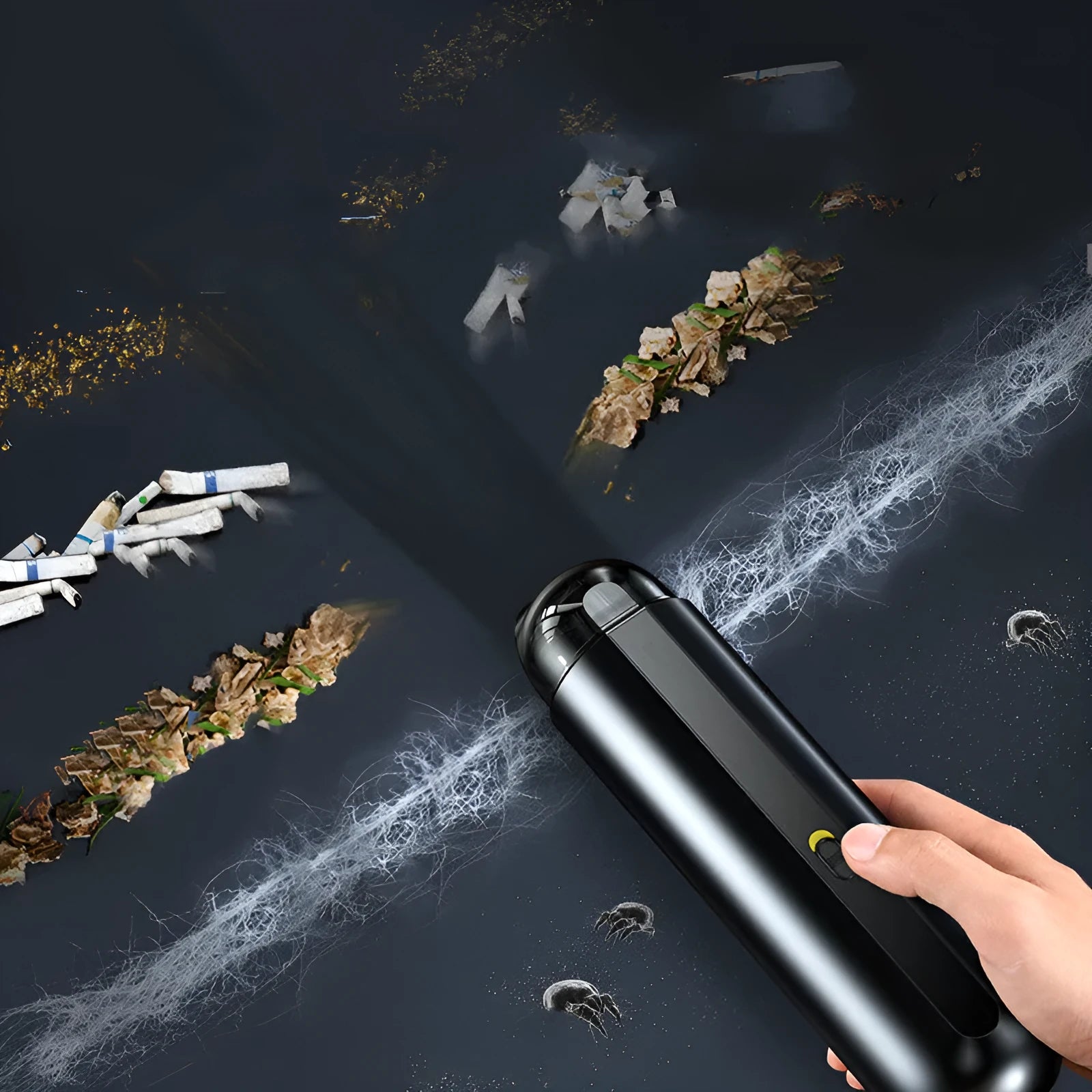 Black cordless handheld car vacuum cleaner with blowing hose attachment on a desktop.