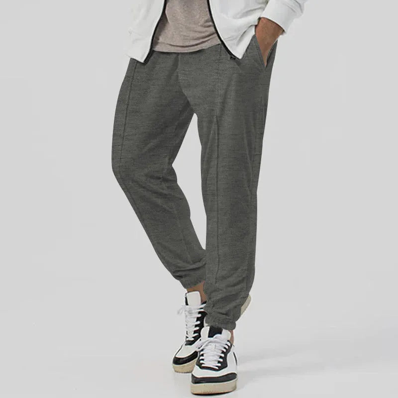 Man wearing gray straight-leg casual track sweatpants with a tapered fit and elastic waistband.