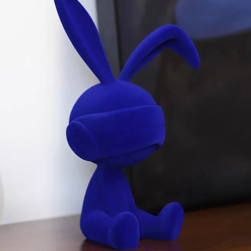 Green suede blindfold rabbit resin table ornament on wooden surface