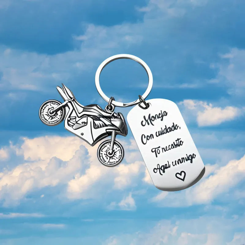 Stainless steel key ring with etched motorcycle design next to a grey flannel drawstring bag.