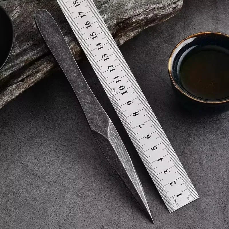 Black stainless steel hand pry tea knife with pointed blade on plain background