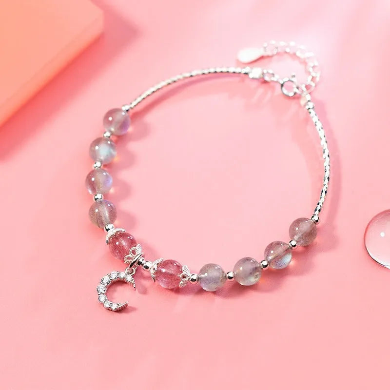 Adjustable natural moonstone bracelet with crescent moon charm on a wrist, showing extension chain.