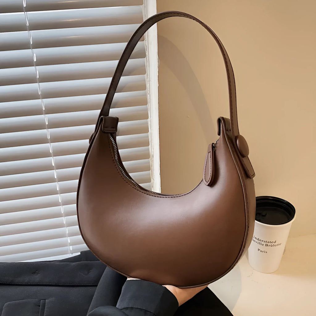 Women's retro dumpling-shaped PU leather shoulder bag in black showing sandwich pockets and zippered compartment
