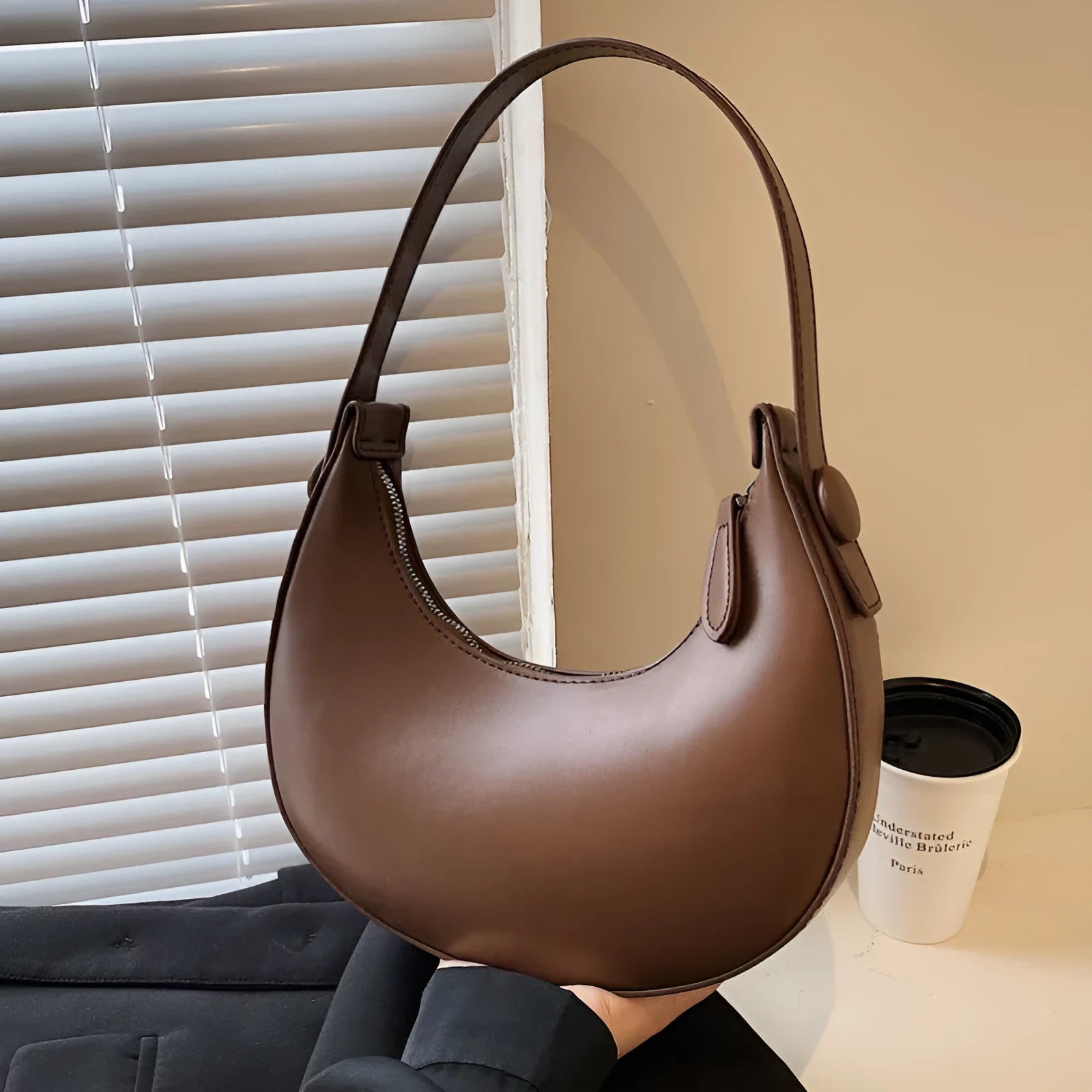Women's retro dumpling-shaped PU leather shoulder bag in black showing sandwich pockets and zippered compartment