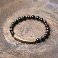 Layered retro ethnic bracelet with natural stone beads and antique brass details on a wrist.