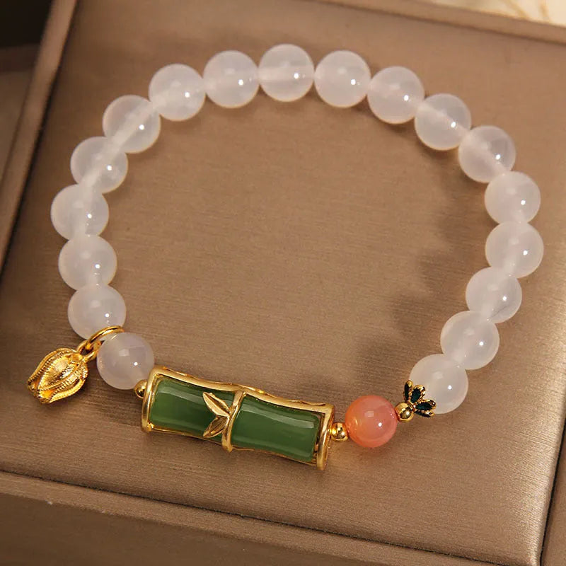 Women's white agate and jade bamboo joint beaded bracelet on a wrist.
