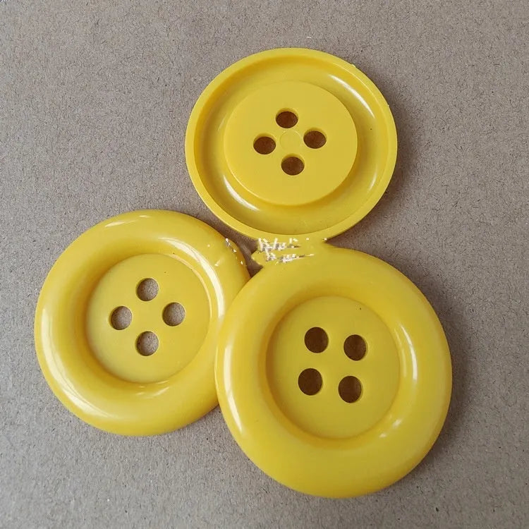 Assortment of oversized round plastic buttons in various colours with four holes.