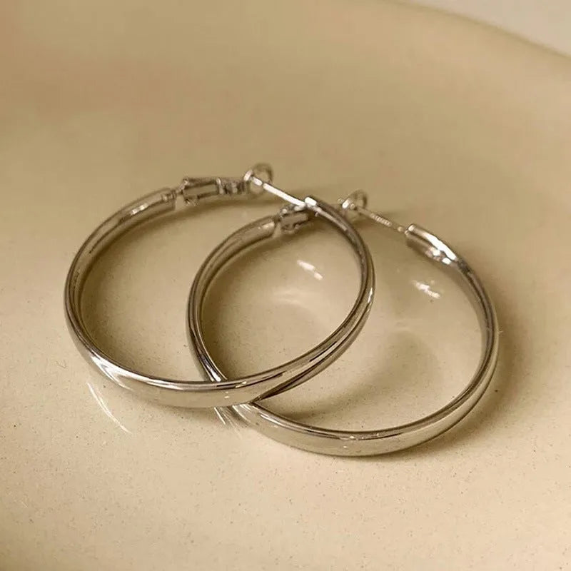 A pair of 40mm diameter metal circle earrings with a gold or silver electroplated finish.