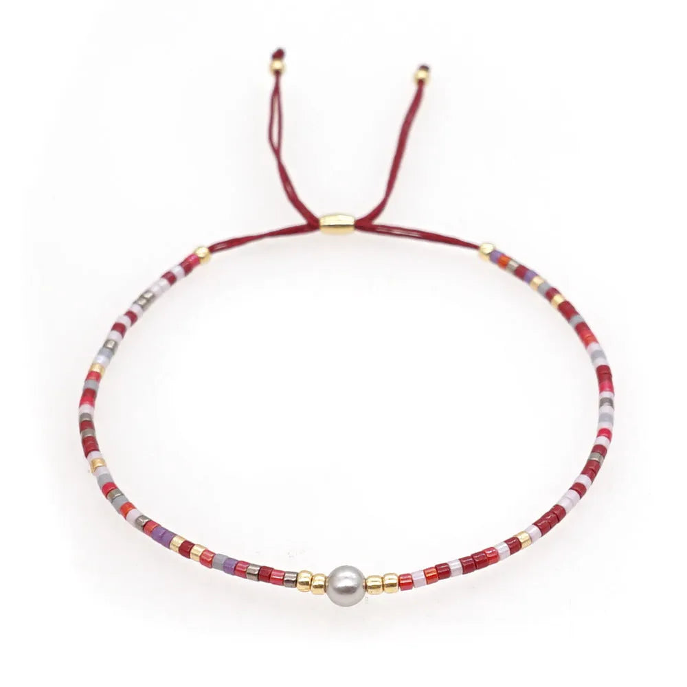 Handmade bohemian-style bracelet with semi-precious stone and colourful glass beads on a wrist.