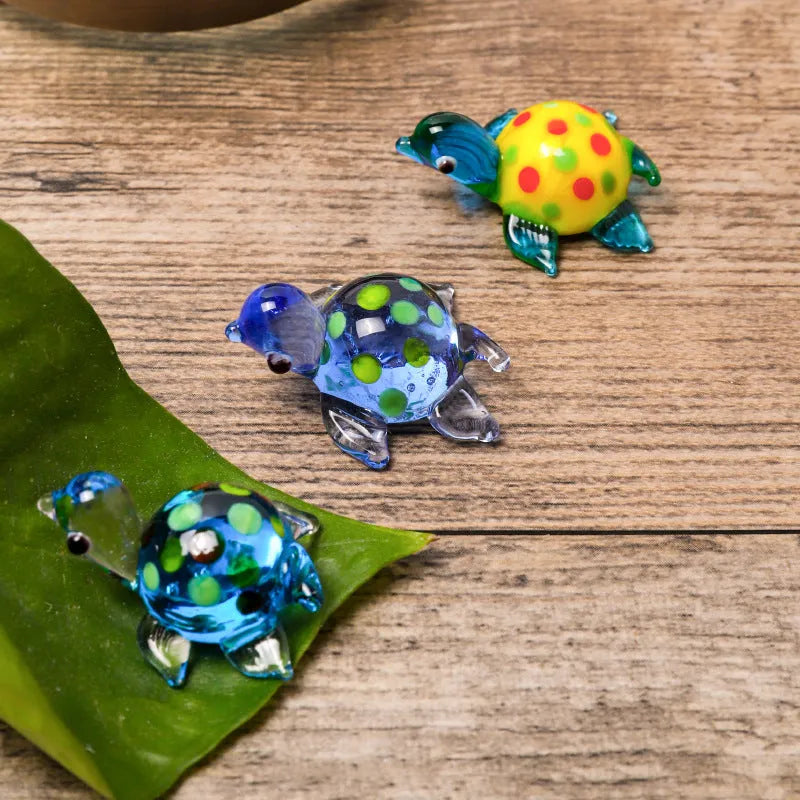 Geometric glass turtle ornament with a blue head and blue shell on a wooden desktop.