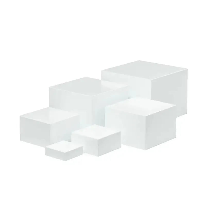 Set of six white geometric cube-shaped plastic dessert display stands arranged on a table.