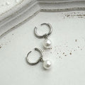 A pair of geometric-shaped women's alloy earrings with a round pearl charm, featuring titanium steel posts.