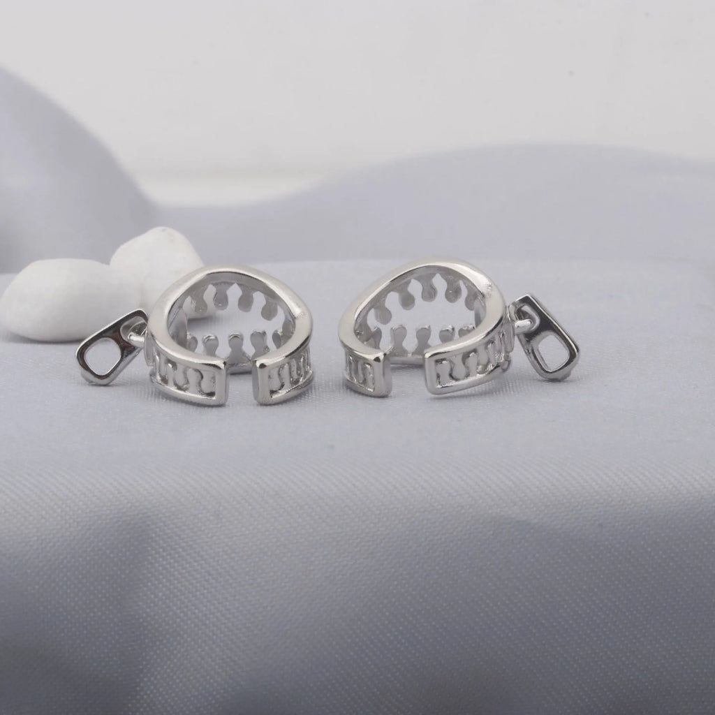 A pair of geometric bone clip earrings made from copper with linear details and an ear clip back.