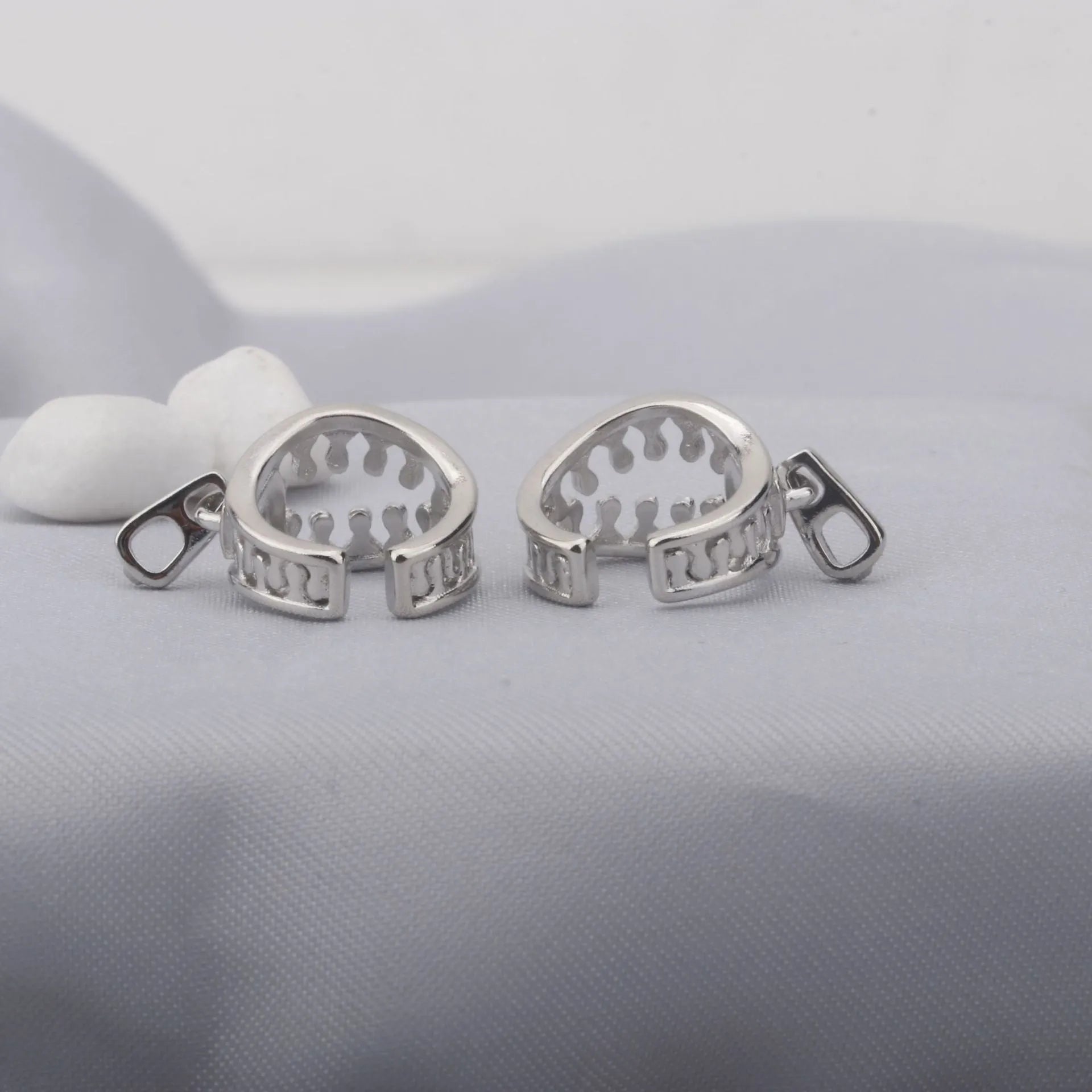 A pair of geometric bone clip earrings made from copper with linear details and an ear clip back.