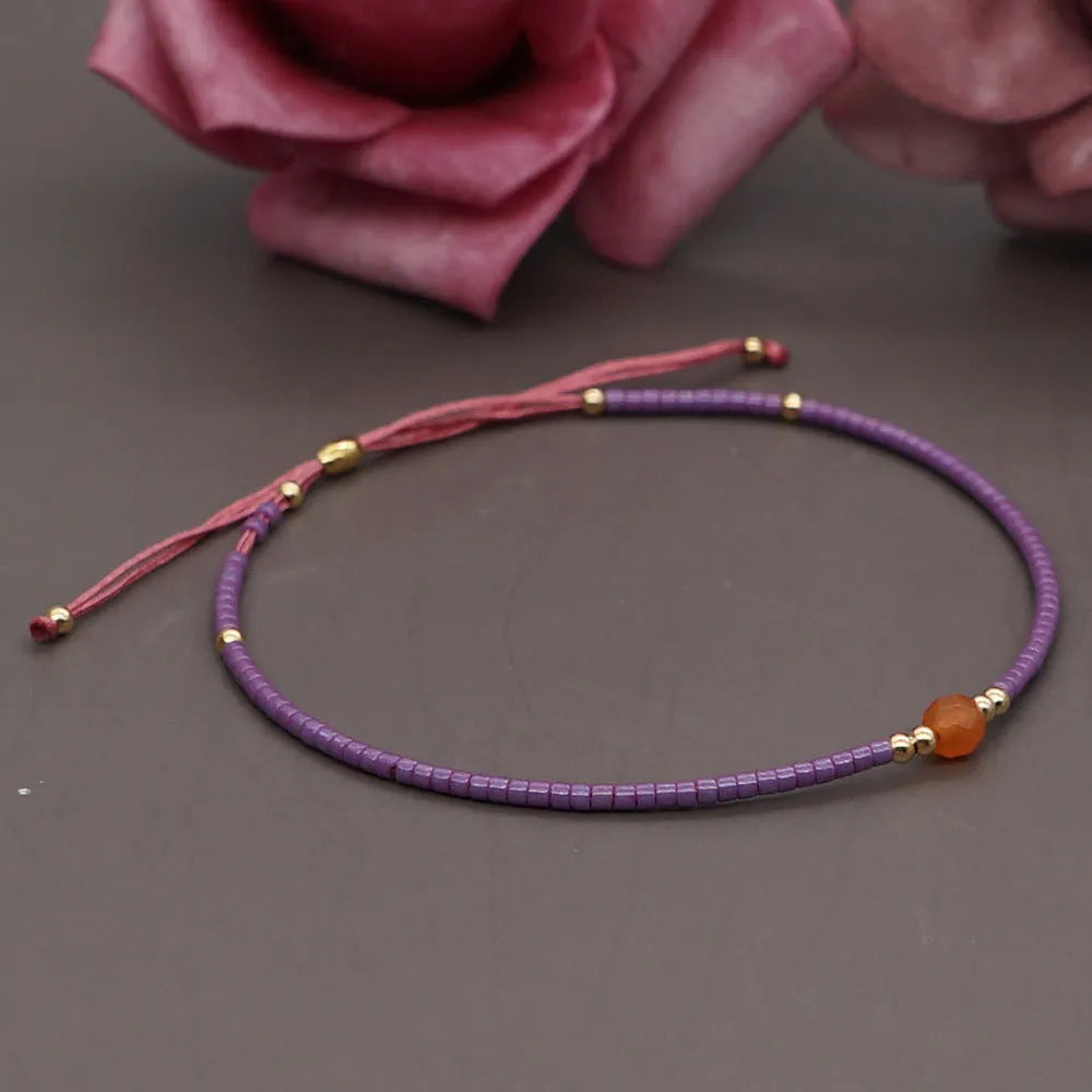 Handmade bohemian-style bracelet with semi-precious stone and colourful glass beads on a wrist.