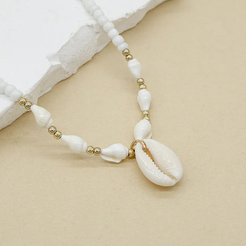 White conch shell bead necklace with mother of pearl pendant on a silver-toned electroplated chain.