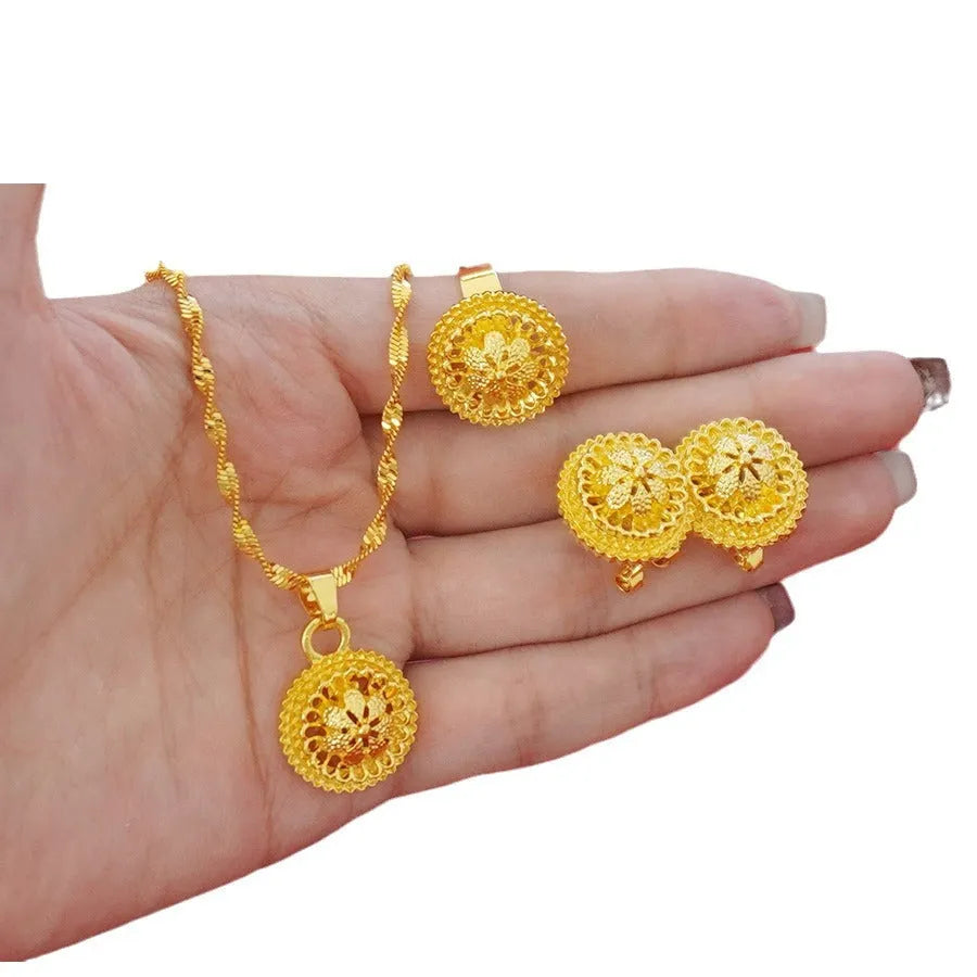 Women's three-piece jewellery set showing gold electroplated necklace with floral pendant, matching earrings, and ring with Middle Eastern design