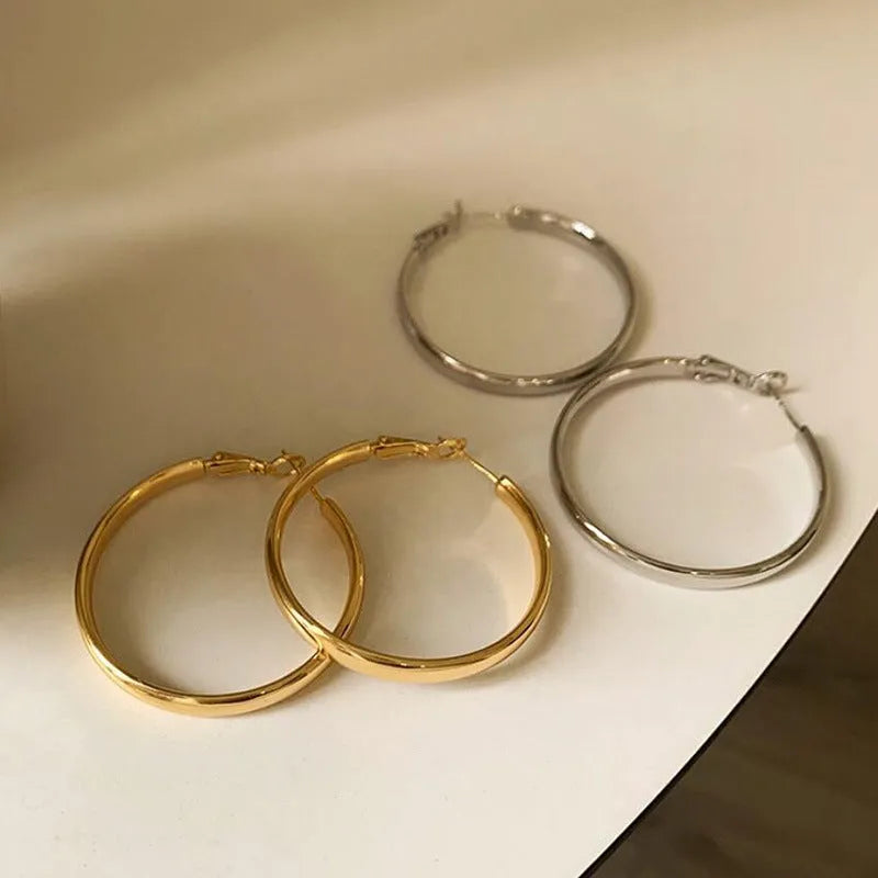 A pair of 40mm diameter metal circle earrings with a gold or silver electroplated finish.