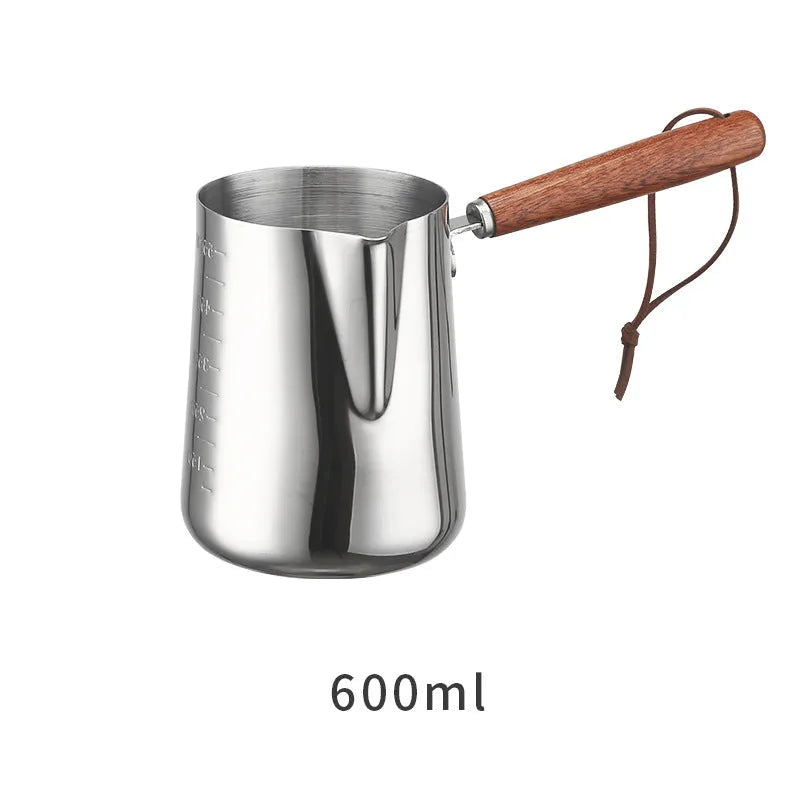 Stainless steel barista milk cup with measurement scale markings and a wooden handle.