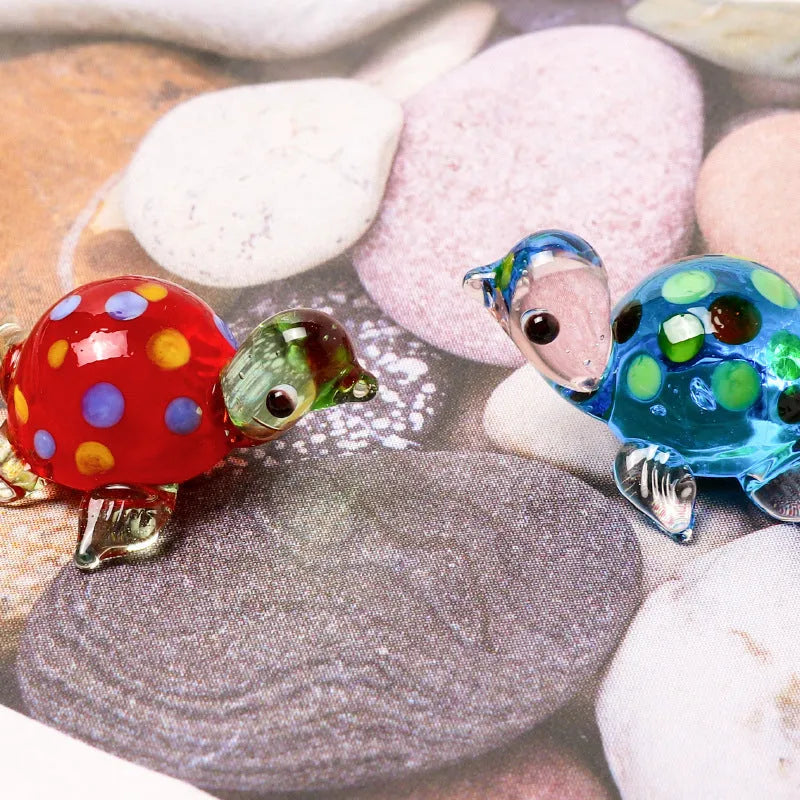 Geometric glass turtle ornament with a blue head and blue shell on a wooden desktop.