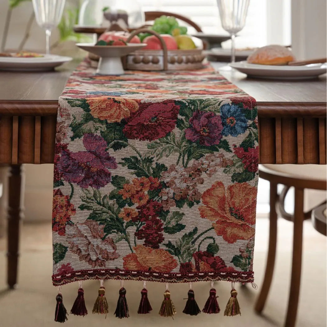 Beige jacquard fabric table runner with long tassels and a woven floral leaf pattern.