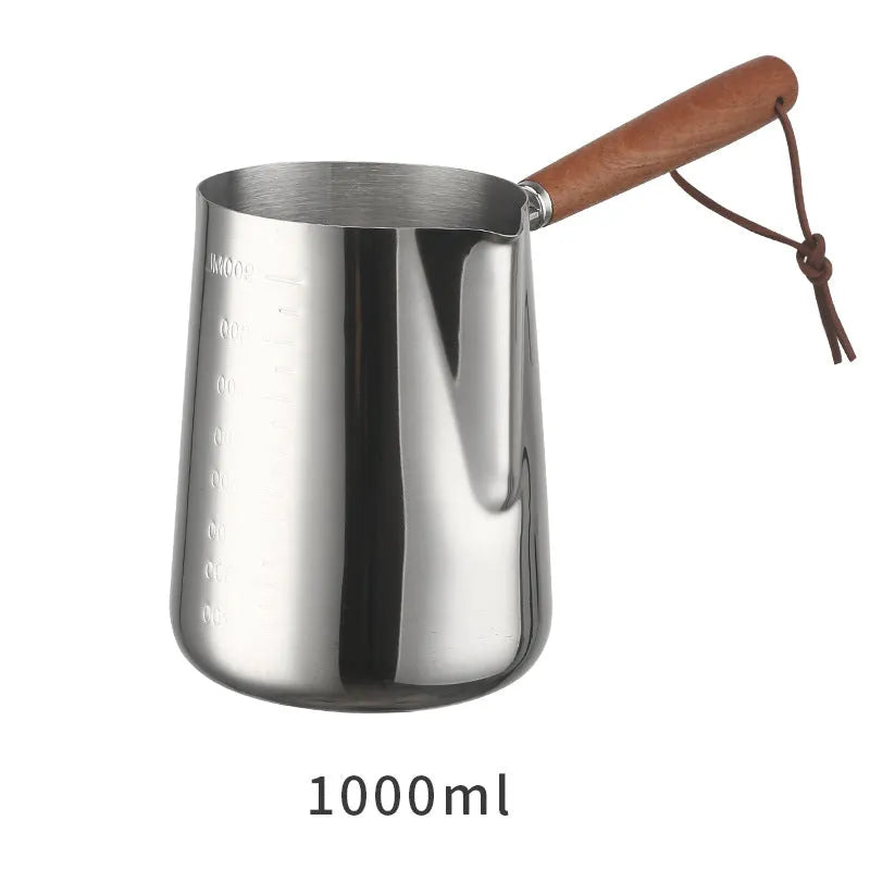 Stainless steel barista milk cup with measurement scale markings and a wooden handle.