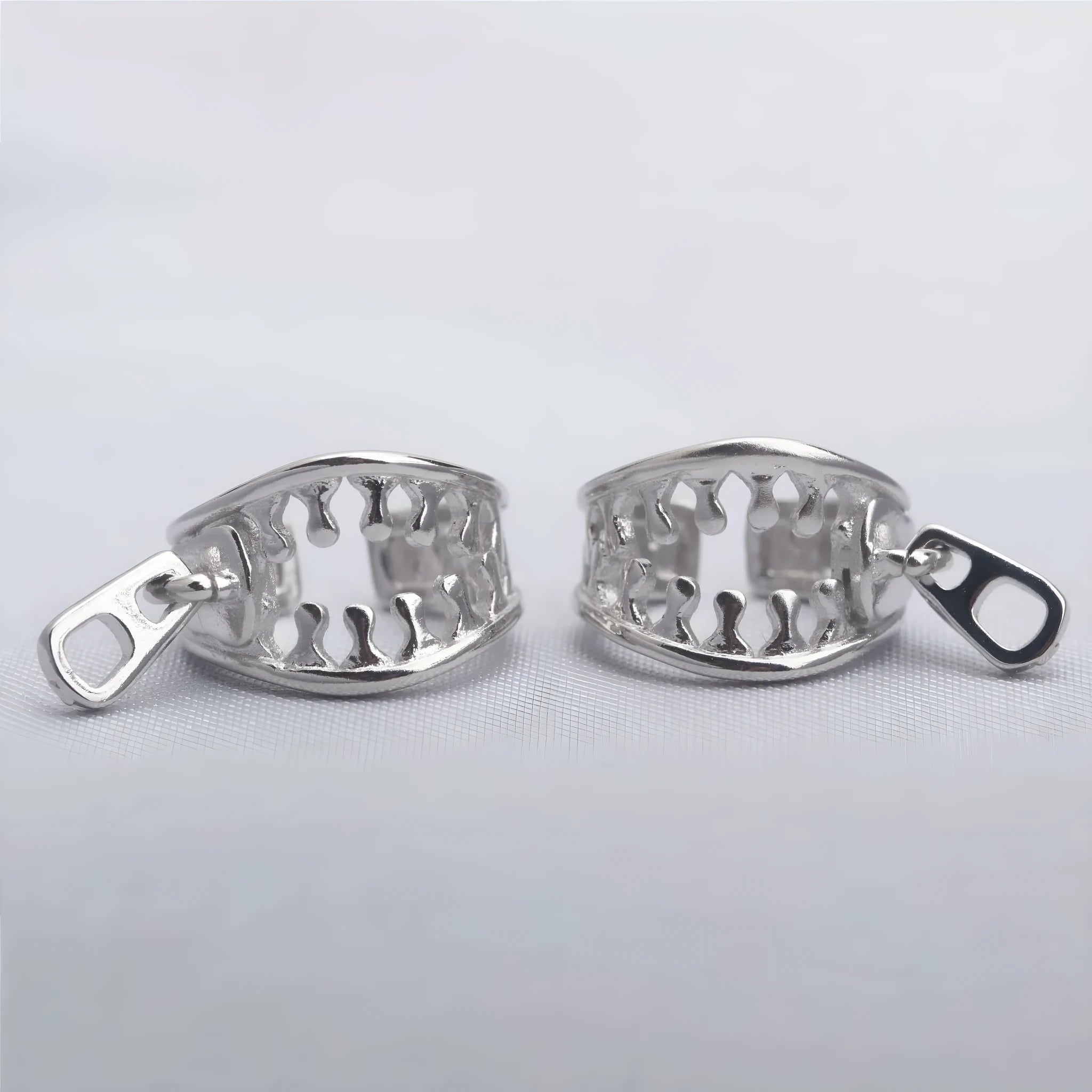 A pair of geometric bone clip earrings made from copper with linear details and an ear clip back.