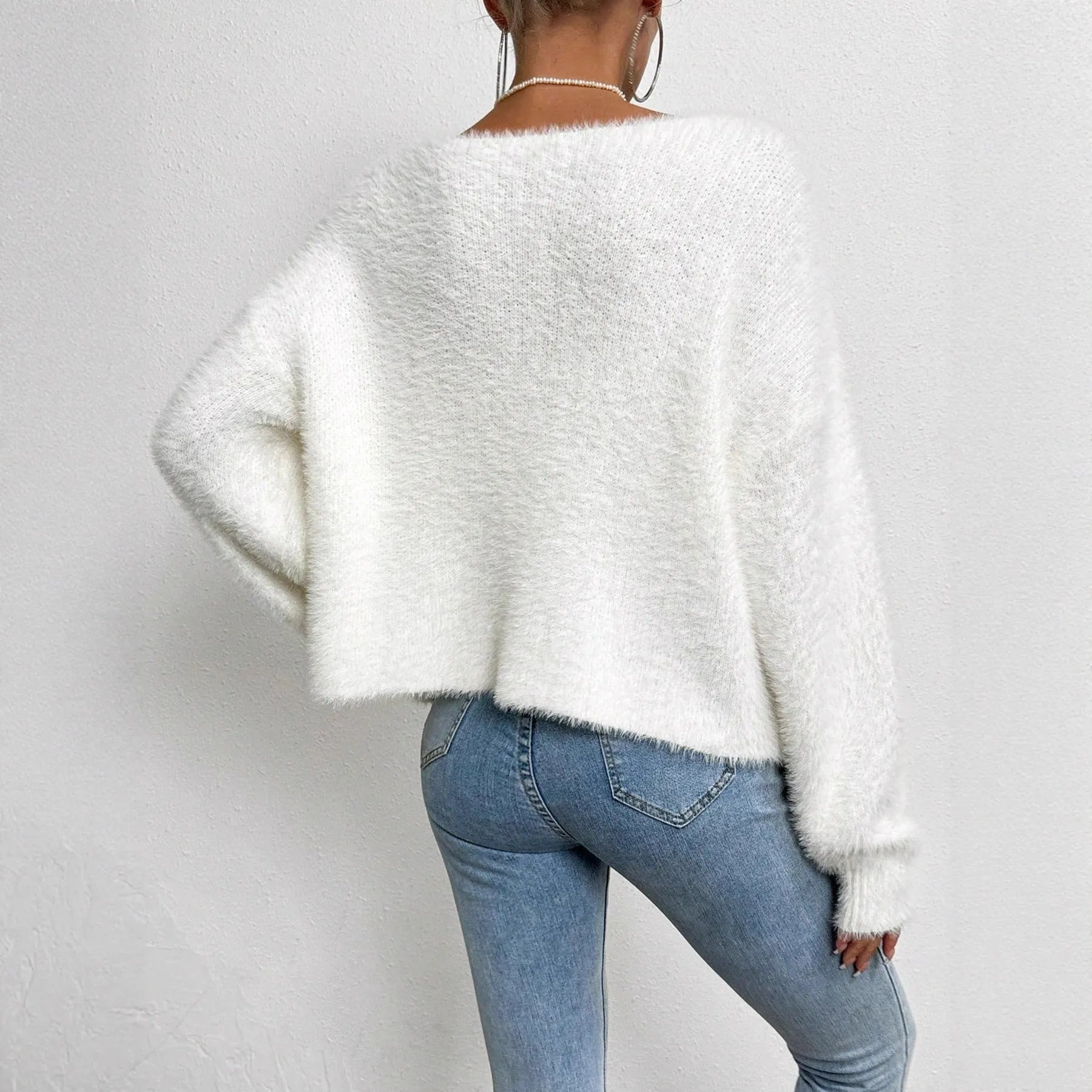 White women's V-neck cardigan sweater with bead knit detail on a hanger.
