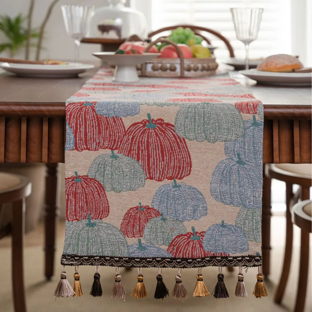 Beige jacquard fabric table runner with long tassels and a woven floral leaf pattern.