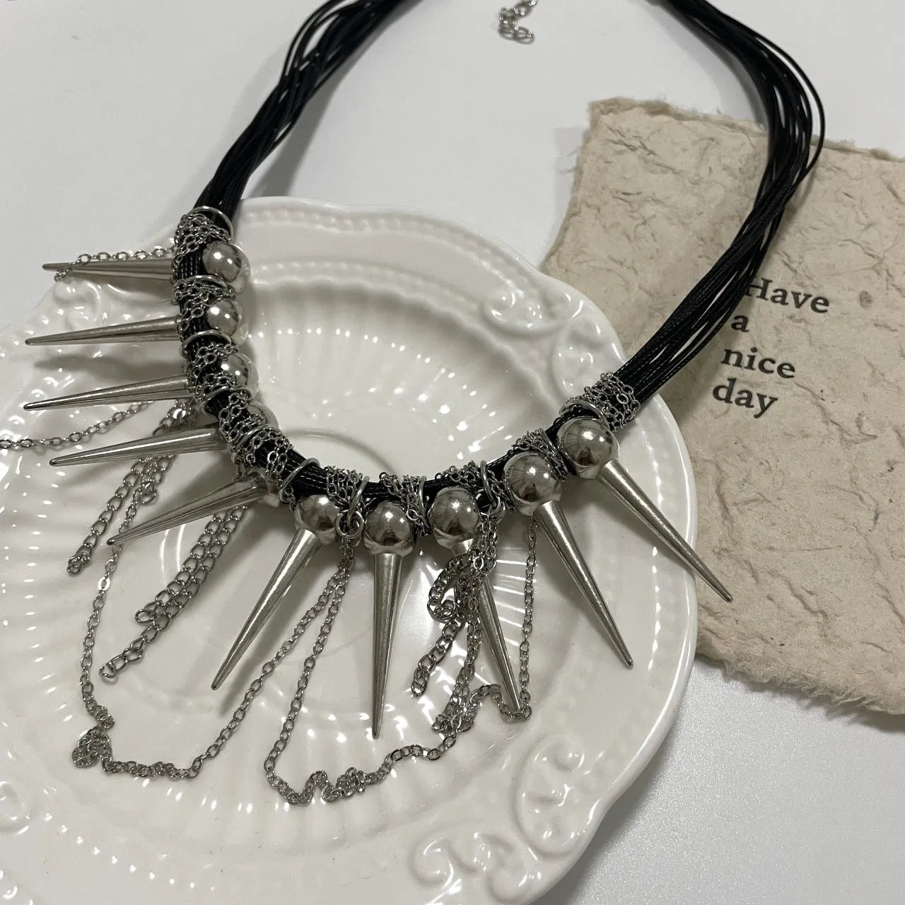 Women's leather necklace with round beads, a winding tassel, and silver point rivets on a casual outfit.