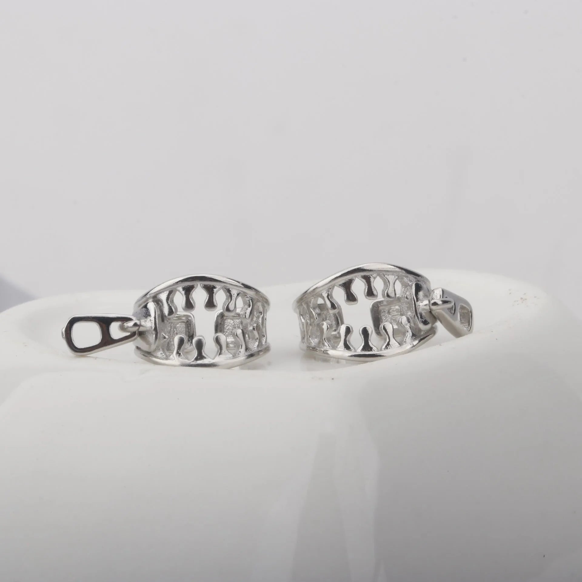 A pair of geometric bone clip earrings made from copper with linear details and an ear clip back.