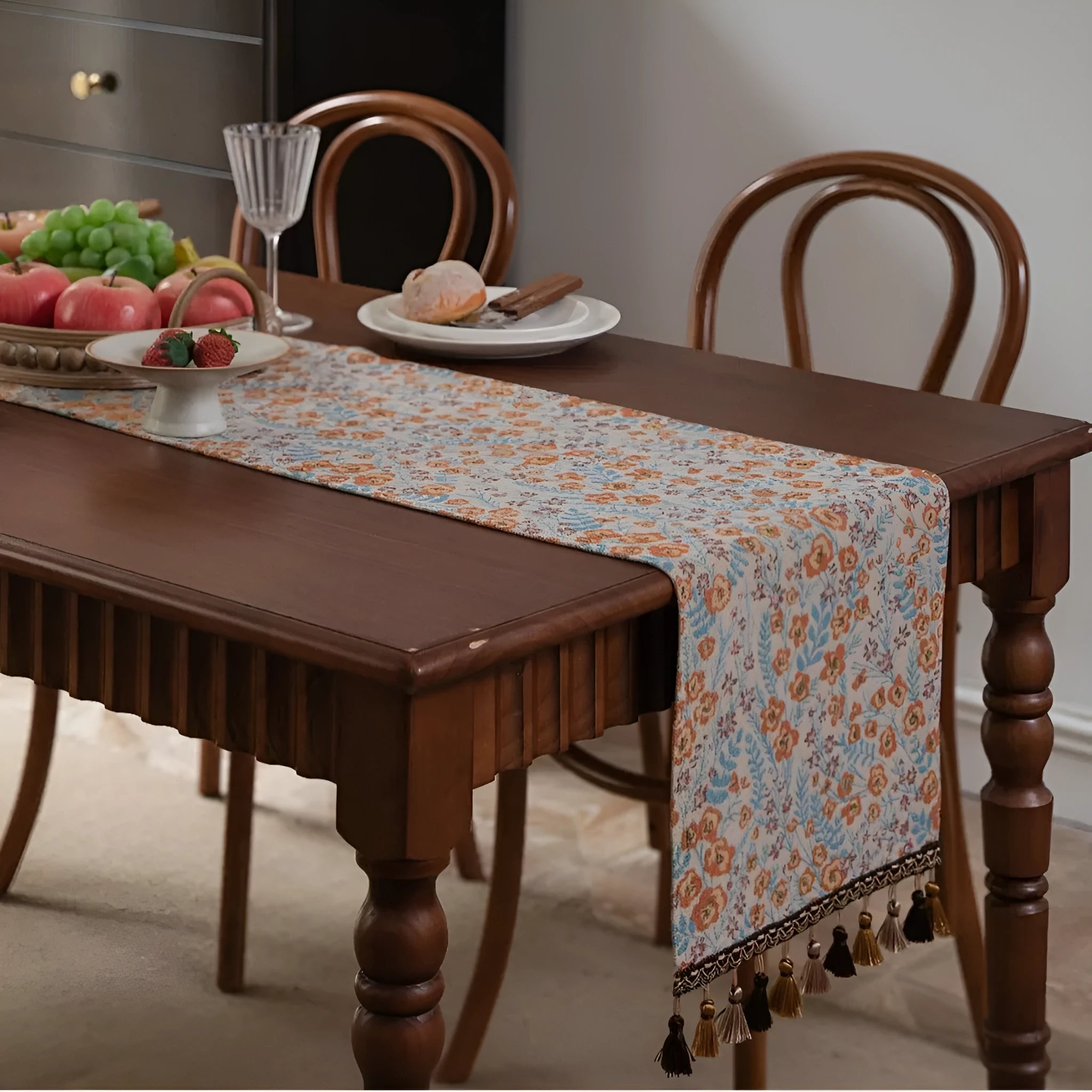 Beige jacquard fabric table runner with long tassels and a woven floral leaf pattern.