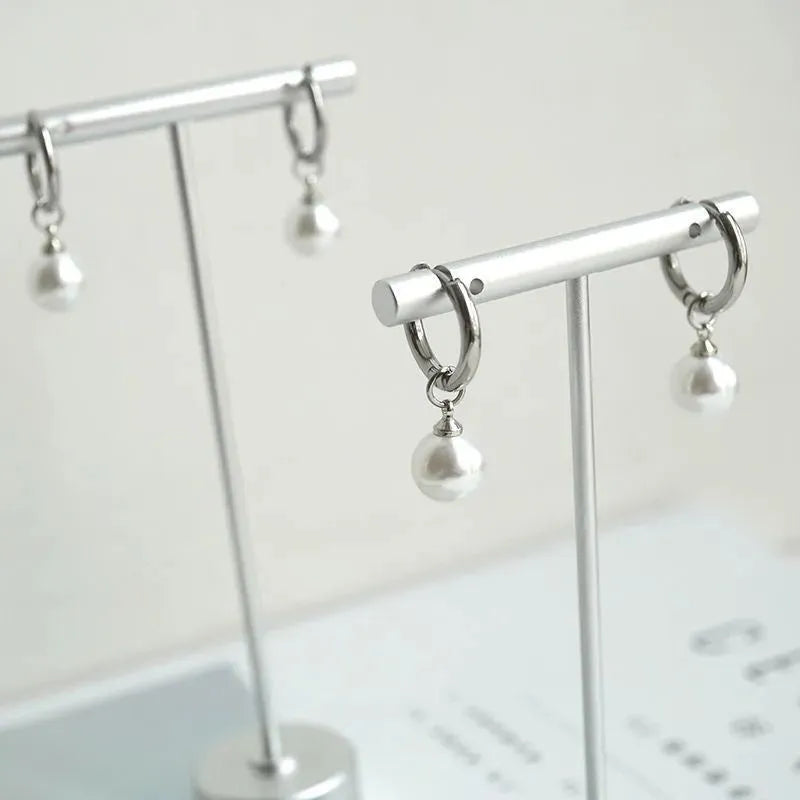 A pair of geometric-shaped women's alloy earrings with a round pearl charm, featuring titanium steel posts.