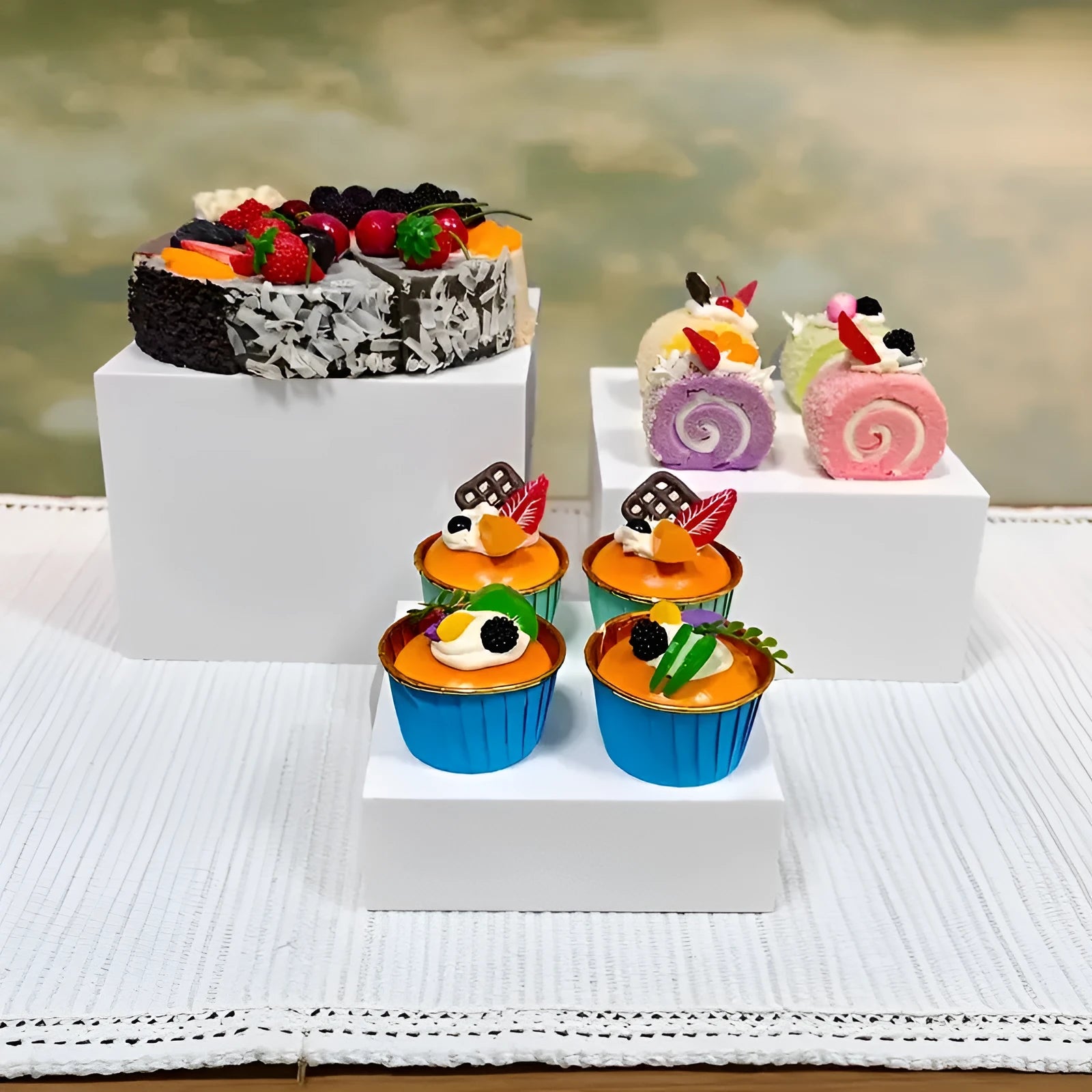 Set of six white geometric cube-shaped plastic dessert display stands arranged on a table.