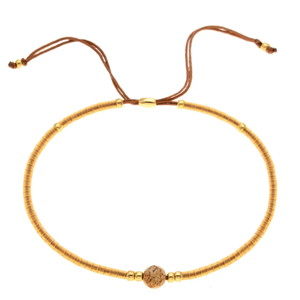 Handmade bohemian-style bracelet with semi-precious stone and colourful glass beads on a wrist.