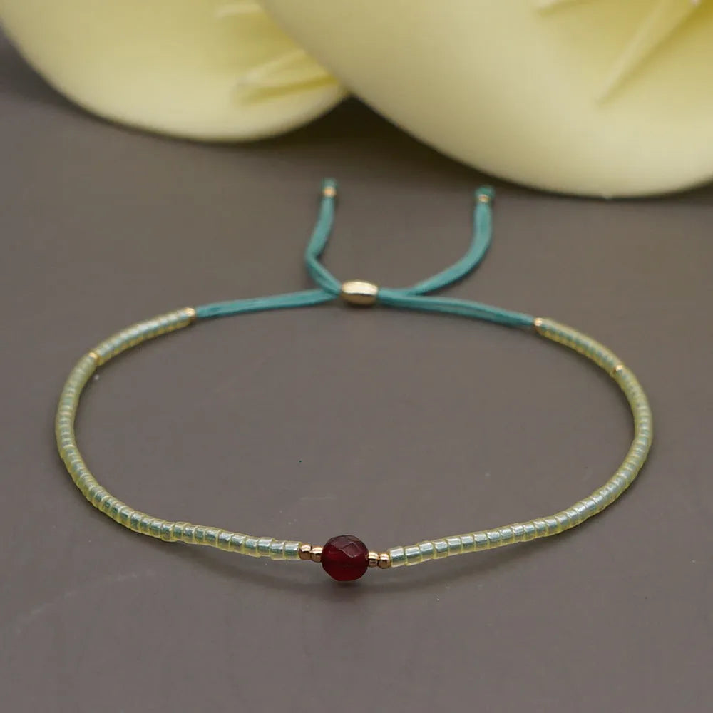 Handmade bohemian-style bracelet with semi-precious stone and colourful glass beads on a wrist.