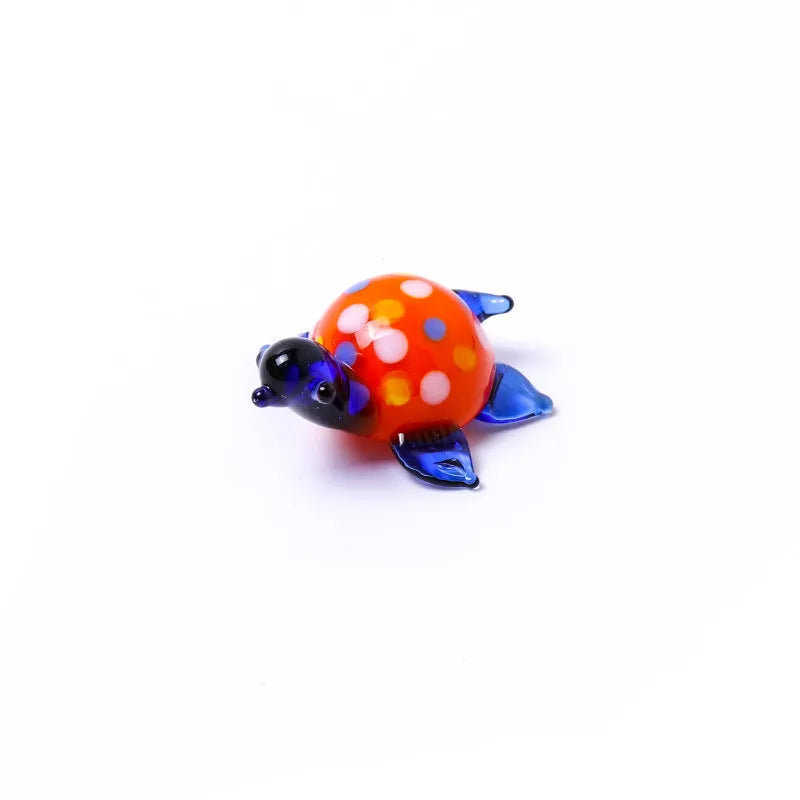 Geometric glass turtle ornament with a blue head and blue shell on a wooden desktop.