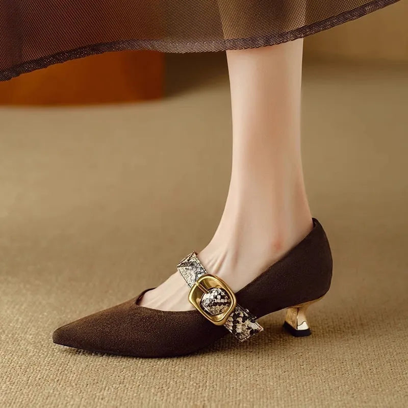 Black pointed toe stiletto high heels with a buckle strap across the instep.