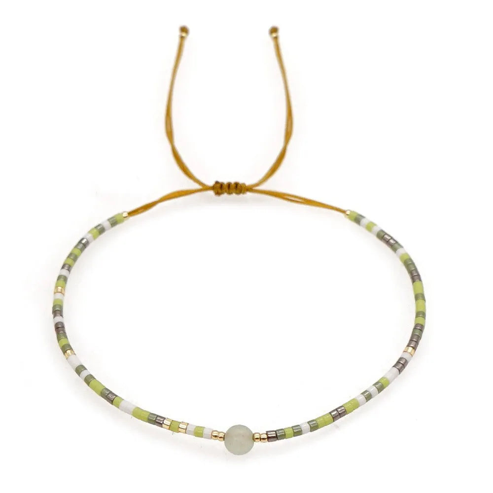 Handmade bohemian-style bracelet with semi-precious stone and colourful glass beads on a wrist.