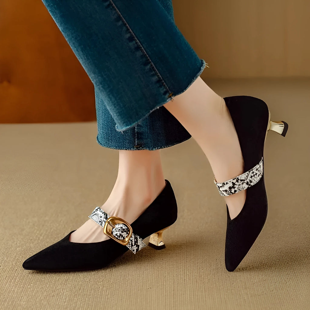 Black pointed toe stiletto high heels with a buckle strap across the instep.