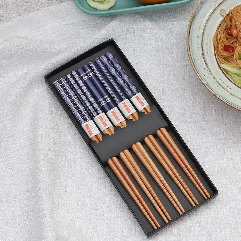 Set of five pairs of bamboo chopsticks with Japanese lucky cat and elegant blue patterns on a table.