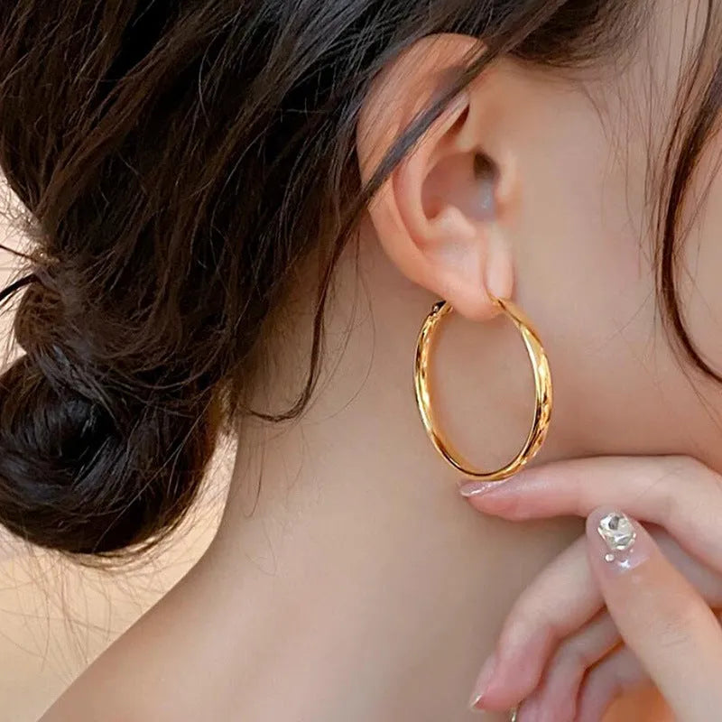 A pair of 40mm diameter metal circle earrings with a gold or silver electroplated finish.