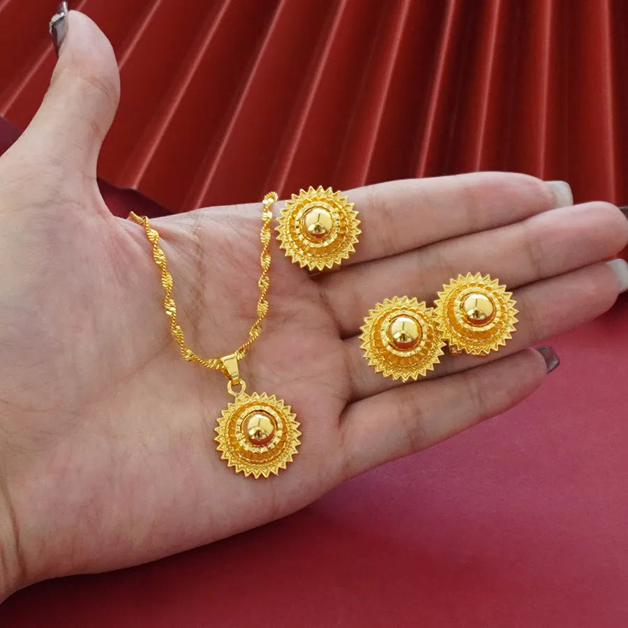 Women's three-piece jewellery set showing gold electroplated necklace with floral pendant, matching earrings, and ring with Middle Eastern design
