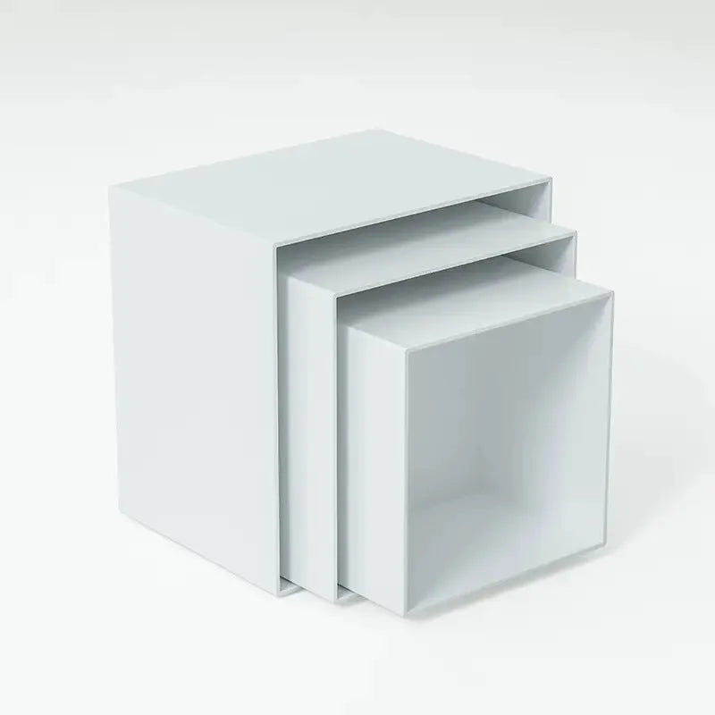 Set of six white geometric cube-shaped plastic dessert display stands arranged on a table.